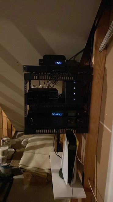 Wall mounted AV rack with receiver and network equipment.
