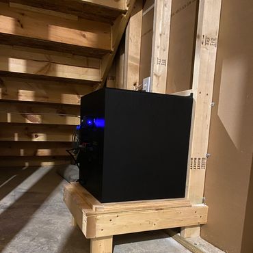 Home theater subwoofer installed on raised platform in basement.