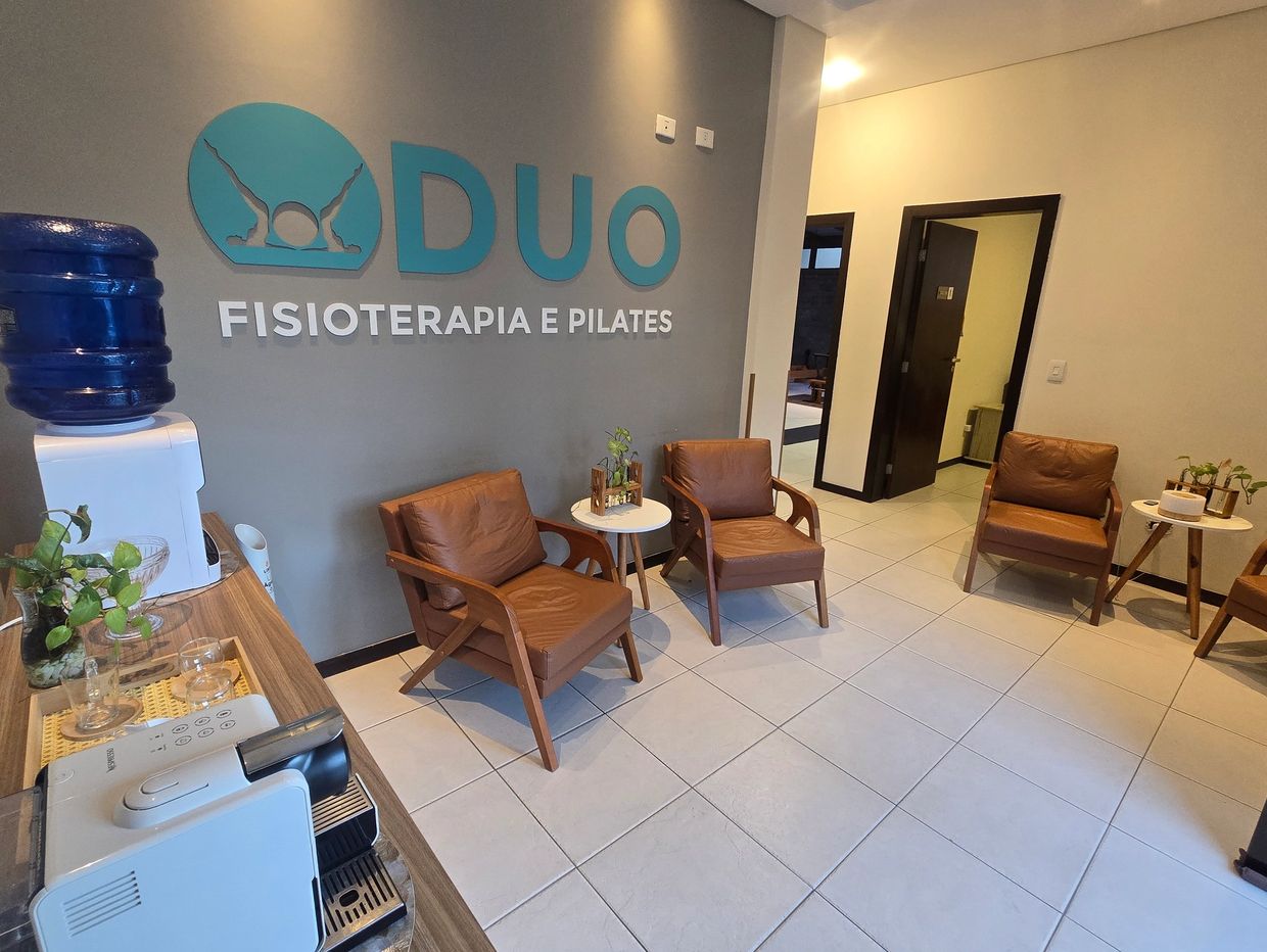 Recepção de clínica ampla logo centralizado em um parede de fundo cinza Duo Fisioterapia e Pilates 
