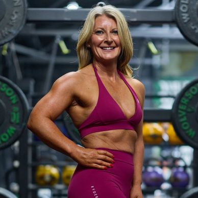 Fit woman in magenta workout attire posing confidently in a gym.