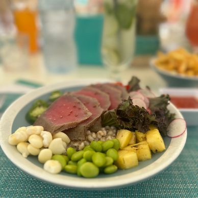 Plate with seared tuna, edamame, pineapple, lettuce, and corn nuts.