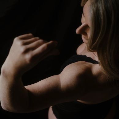 Woman flexing arm muscle in dim lighting.