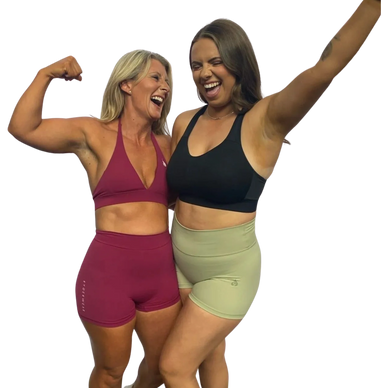 Two joyful women in workout attire, celebrating and smiling together.
