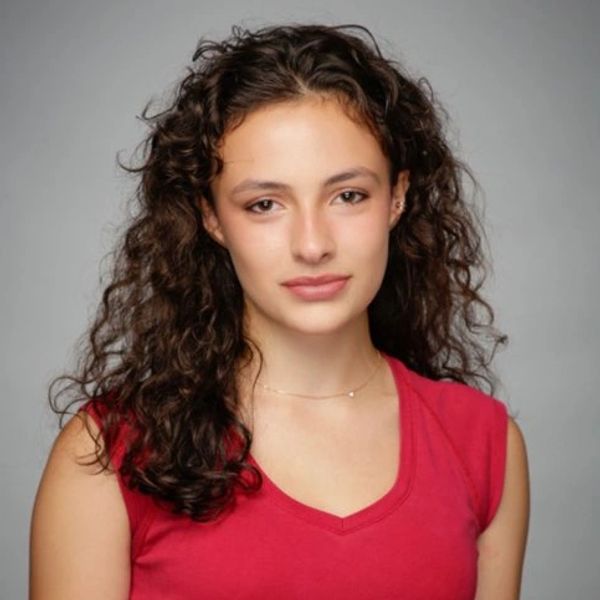 Young woman with curly hair wearing a red sleeveless top.