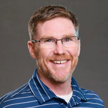 Smiling man with glasses in a blue striped shirt.