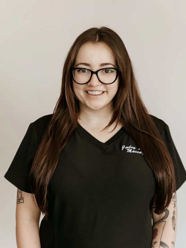 Smiling woman with long brown hair and glasses wearing a black shirt.