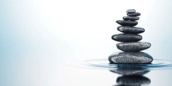 Stack of balanced smooth stones on water with soft ripples.