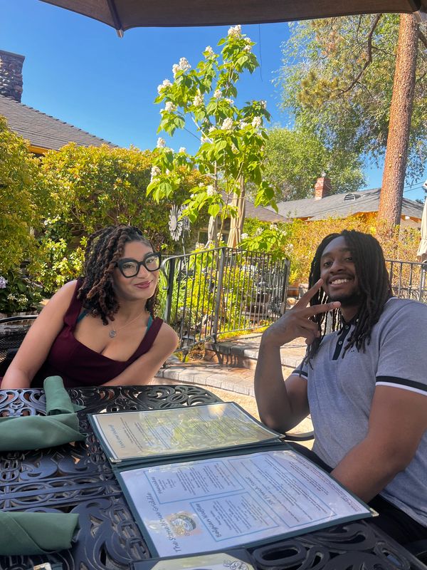 Two friends enjoying a sunny day outdoors, one flashing a peace sign.