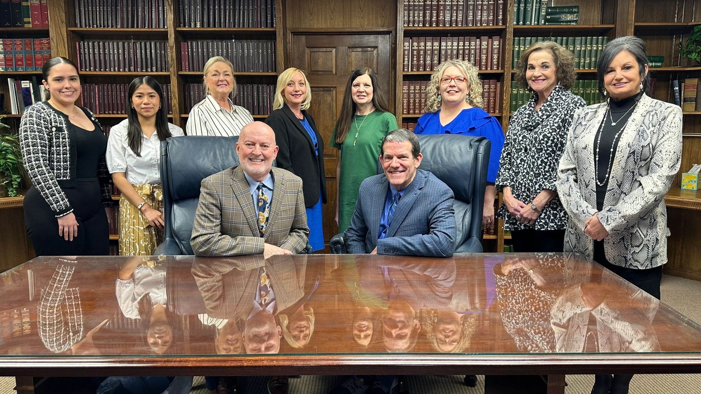 Group portrait of ten people in a library setting, dressed in formal attire.