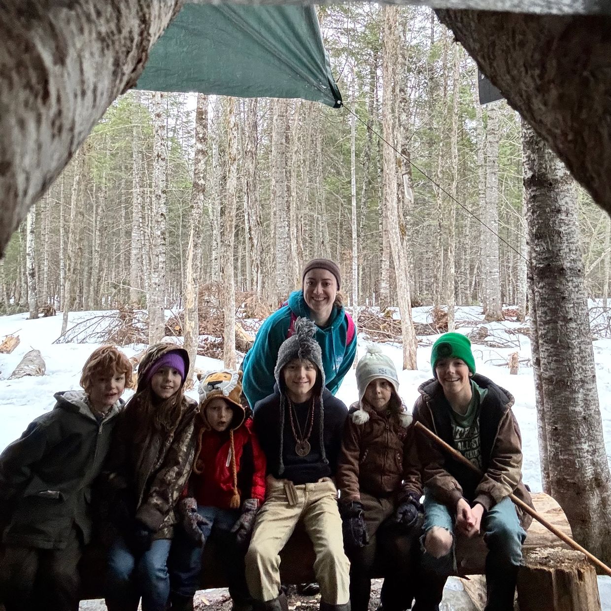 Group of kids and an adult outdoors in winter.