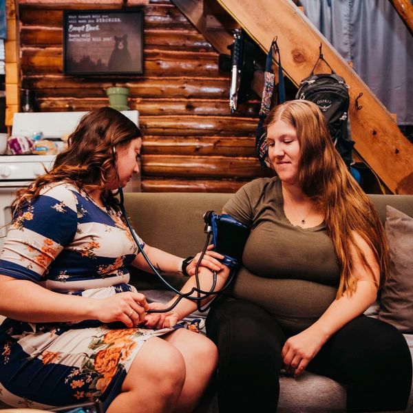 Woman checking another woman's blood pressure indoors.