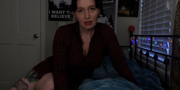 Woman sitting on bed in dimly lit room.