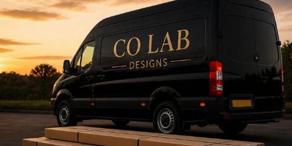 Black delivery van with CO LAB Designs logo parked near stacked packages at sunset.
