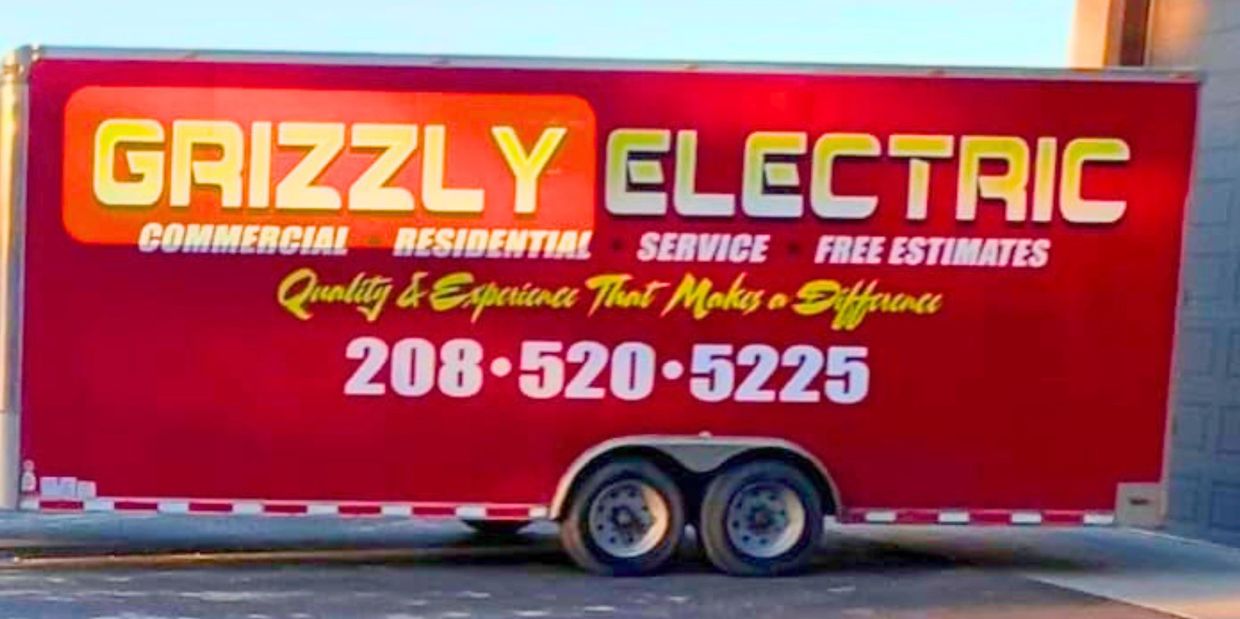 Red trailer with Grizzly Electric advertisement and contact number.