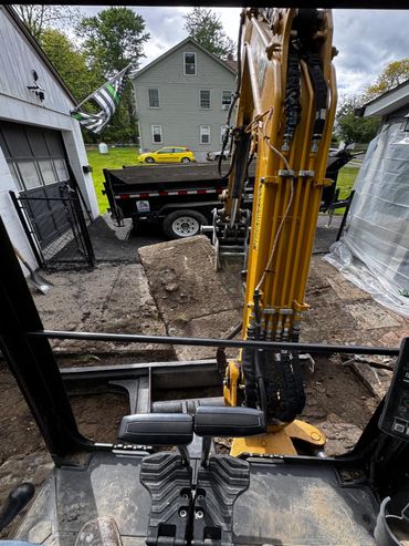 View from inside a construction excavator digging up a driveway.