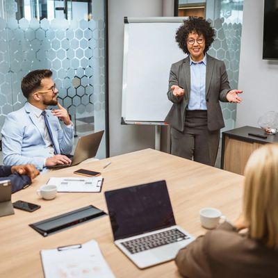 Woman presenting to colleagues in a modern office meeting room.