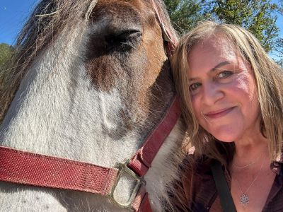 Woman posing with a horse outdoors.
