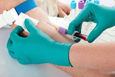 Blood being drawn from an arm with gloves on.