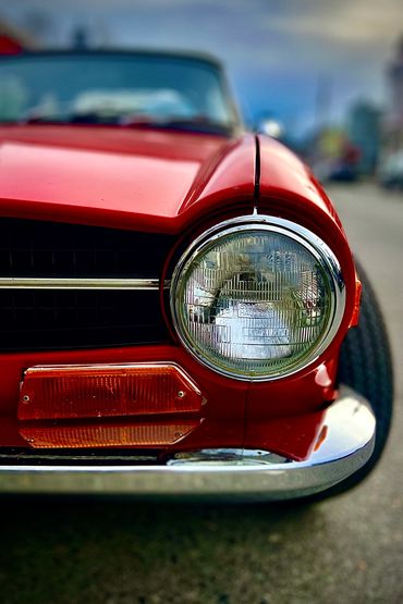 Close-up of a red classic car's headlight and front details.