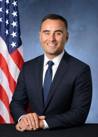 Man in suit posing with American flag backdrop.