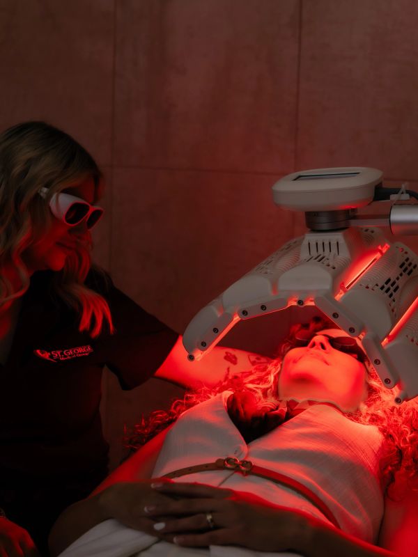 A woman receiving a red light therapy treatment on her face.