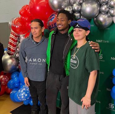 Three guests posing together in front of red and silver balloons at a BFLO Photobomb event.