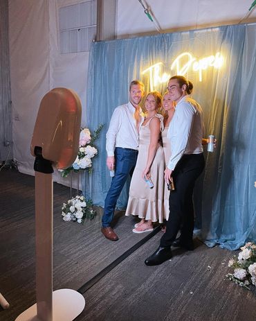 Couple posing together at the BFLO Photobomb photo booth against a warm golden curtain backdrop.