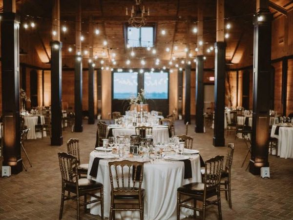 Elegant banquet tables set in a warmly lit rustic hall with string lights.