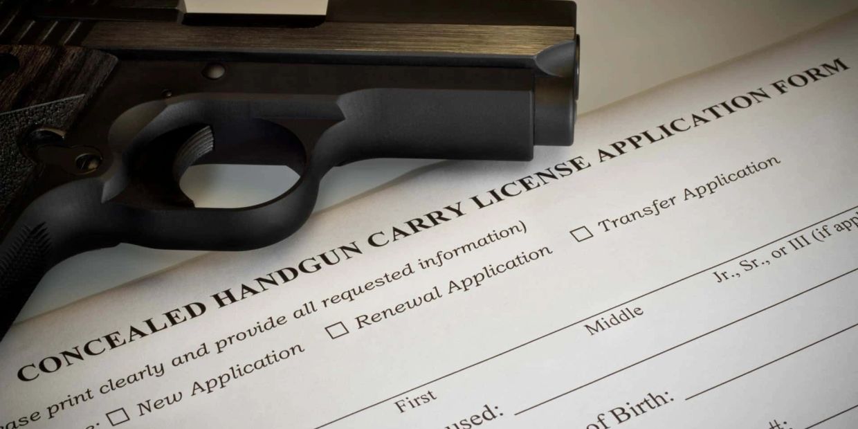 A handgun resting on a concealed carry license application form.
