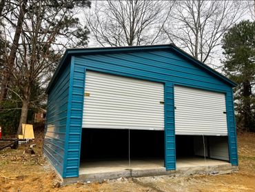 Blue metal garage with two white roll-up doors, partially open.