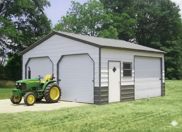 Metal garage with three roll-up doors and a green tractor parked outside.