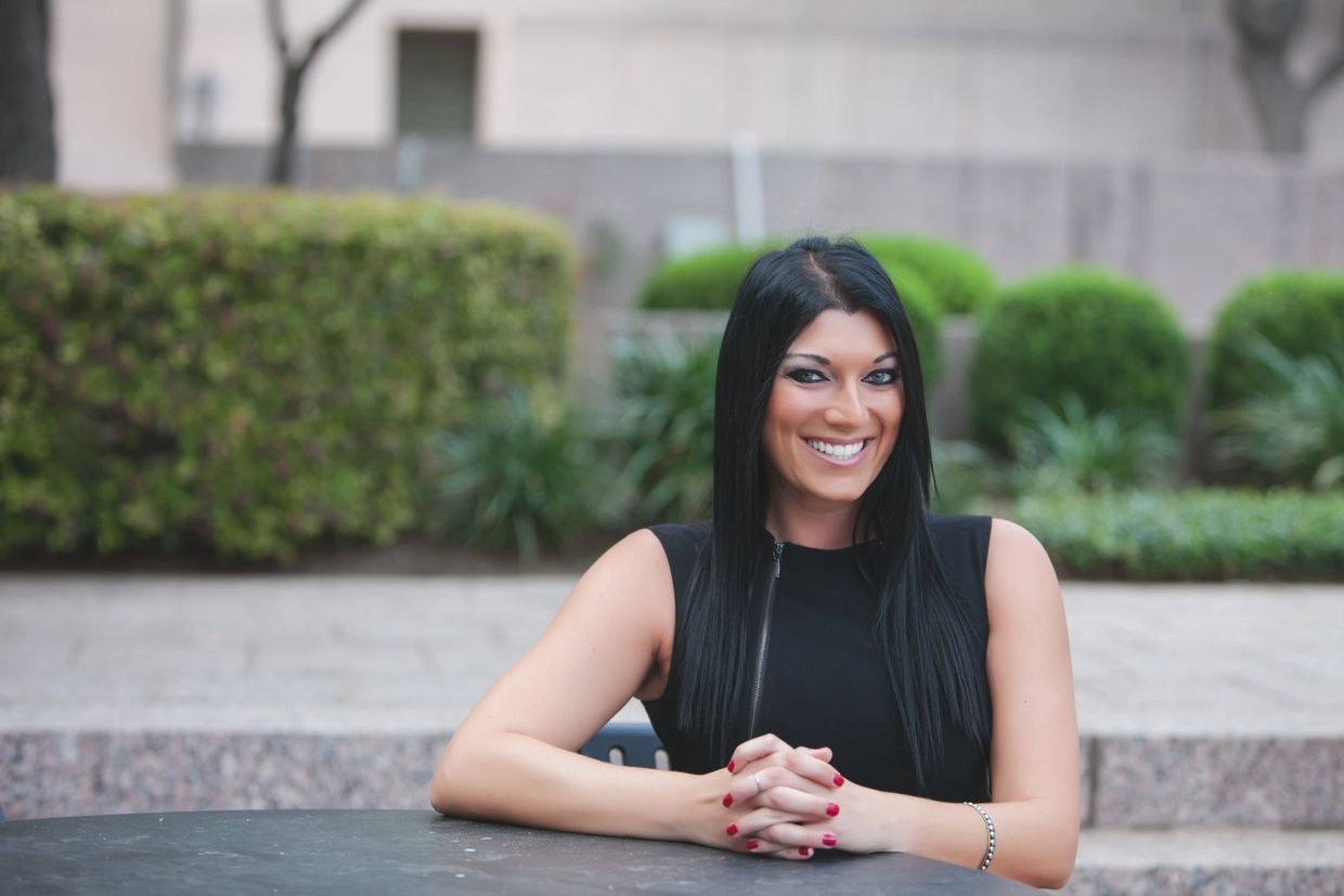 Mujer sonriente con cabello largo y oscuro, vestida de negro.