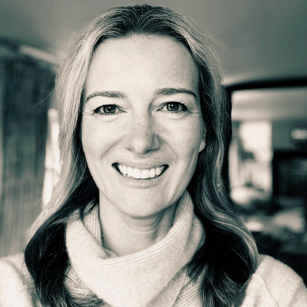 Woman smiling warmly in a cozy indoor setting.