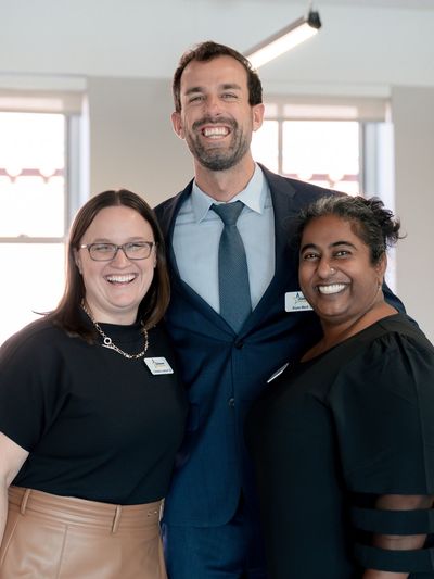 Three smiling colleagues posing together in a bright office.