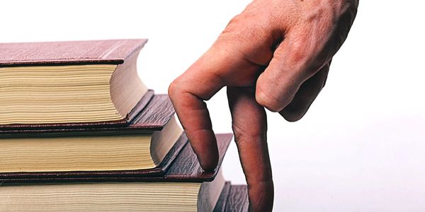 Hand with fingers walking up a stack of books