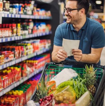 Man happily shopping with a grocery cart full of fresh produce.