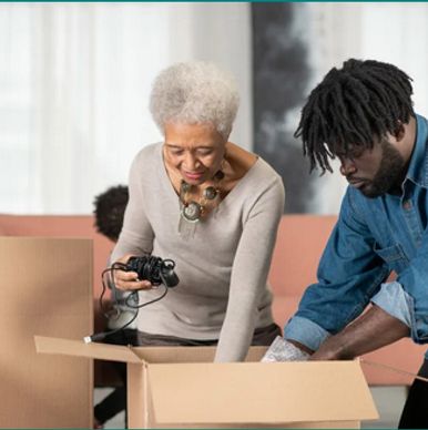 Two people unpacking boxes in a bright room, sorting items together.