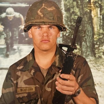 Young soldier in camouflage holding a rifle.