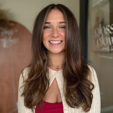 Smiling young woman with long brown hair and a cream cardigan.