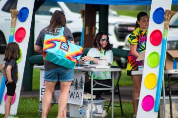 People interacting at a colorful outdoor booth at an event.