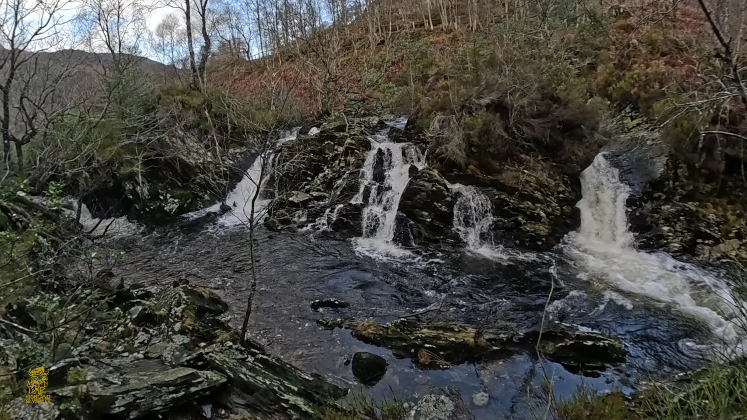 A serene multi-tiered waterfall flowing through rocky terrain in a forested area.