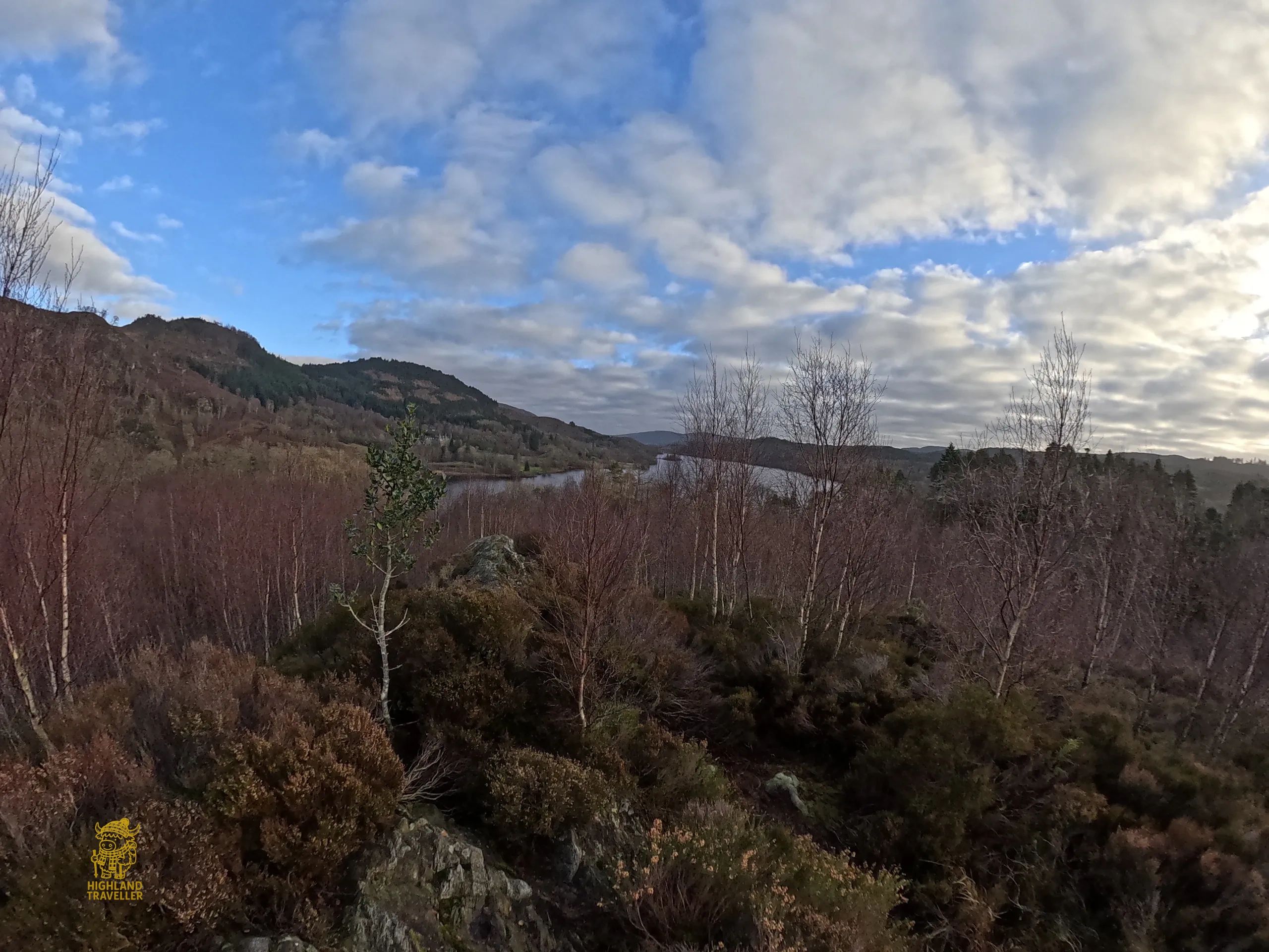 Scenic view of a mountainous landscape with a lake and cloudy sky.