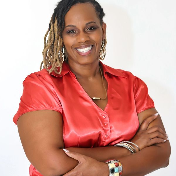 Confident woman smiling with arms crossed, wearing a red blouse.