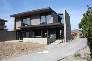 Modern two-story house with large windows and a long driveway.