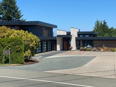 Modern house with sleek black and white design and large driveway.