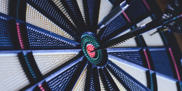Darts hitting the bullseye on a dartboard.