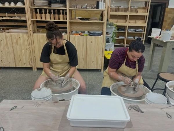 Two women working on pottery wheels in a workshop.