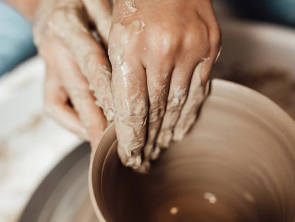 Hands shaping clay on a pottery wheel.