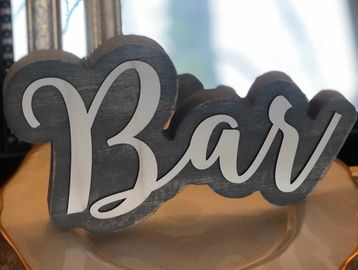 A decorative wooden sign with the word 'Bar' in cursive.