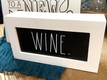 Decorative sign with the word 'WINE.' in white on a black background.
